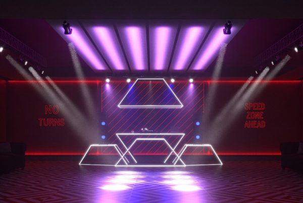 فضای DJ با نورپردازی بنفش و قرمز و طراحی هندسی در دیوار و میز.